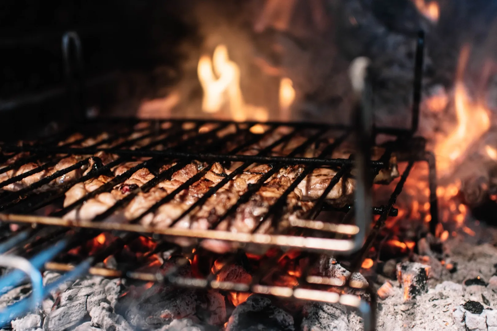 Cooking meat on the grill in a fireplace with embers.